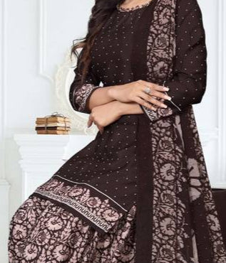Woman wearing a black and brown traditional outfit with floral patterns in a white room.