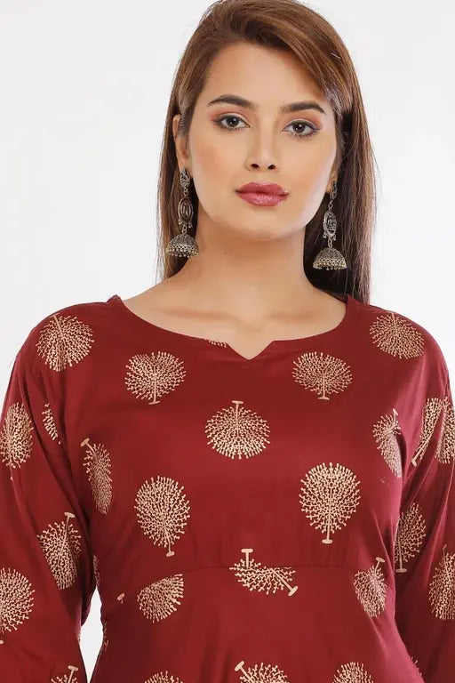 Woman wearing a red dress with gold tree patterns on a white background