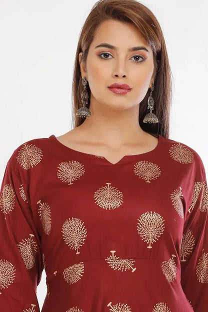 Woman wearing a red dress with gold tree patterns on a white background