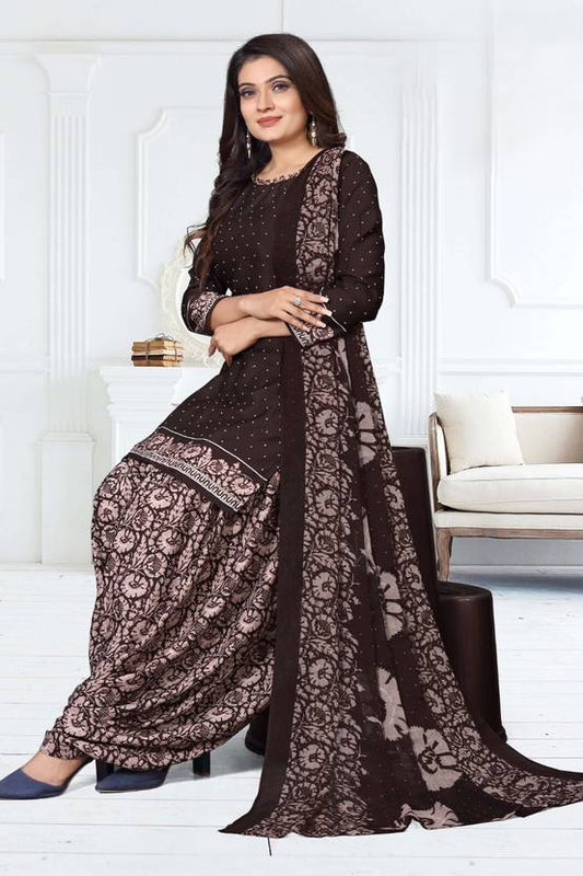Woman wearing a black and brown traditional outfit with floral patterns in a white room.